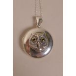 A silver pendant locket, the front with applied cast silver owl's head with stone set eyes