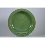 A large Chinese green crackle glazed pottery charger with a lobed rim and incised dragon decoration,