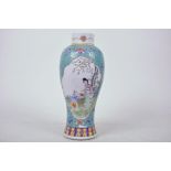 A Chinese famille verte porcelain vase decorated with panels of figures in a garden in bright