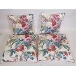 A set of four cotton chintz cushions, with piping, leather pads and zips to each, two of 15"