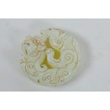 A Chinese light green hardstone pendant with carved mythical creature decoration, 2" diameter