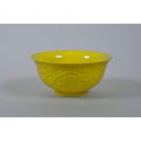 A Chinese yellow glazed porcelain rice bowl with raised decoration of a dragon and phoenix chasing