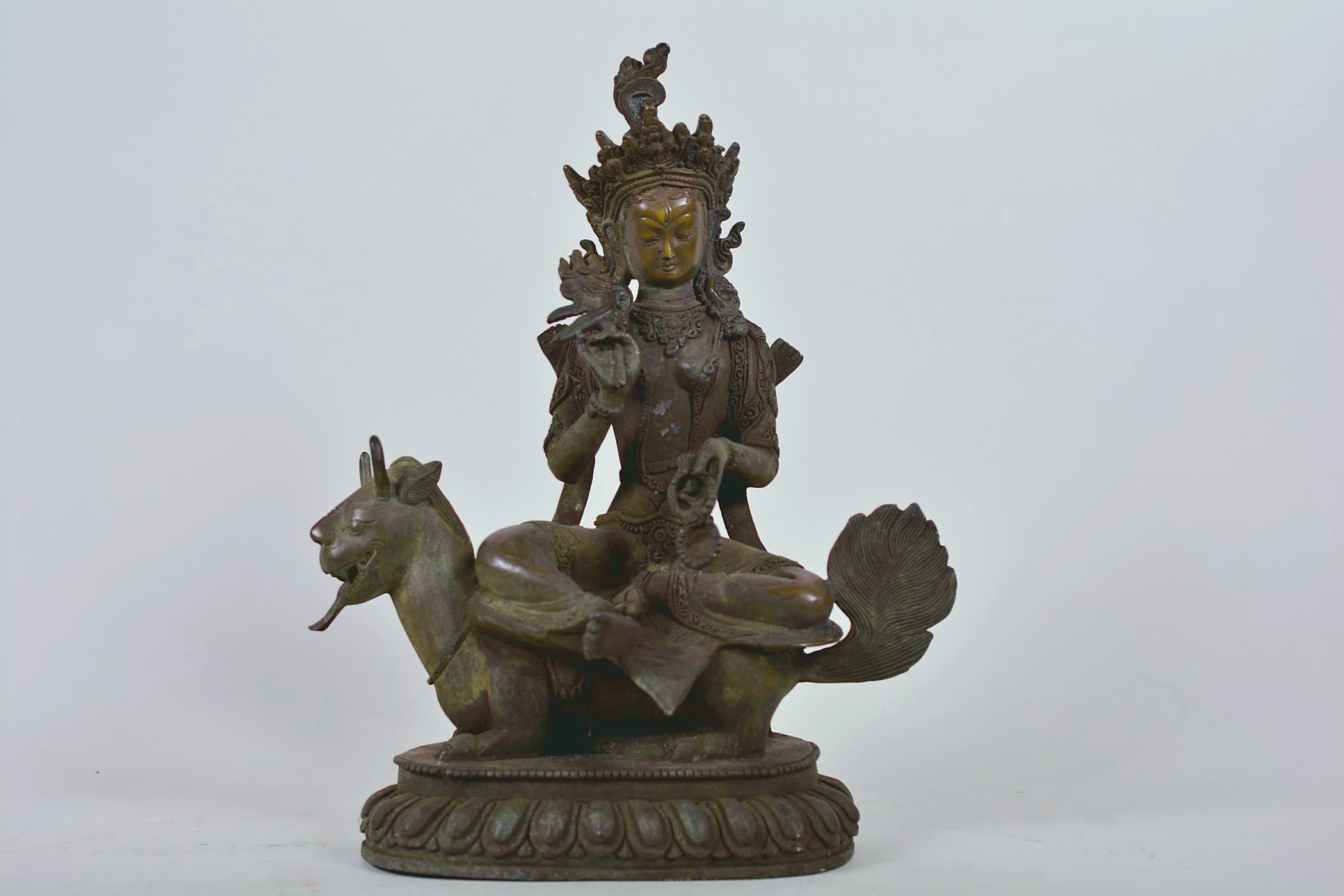 A Chinese patinated bronze figure of Buddha seated on a mythical beast, 10" high