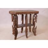 A Burmese teak two tier occasional table, with carved elephant decoration and scrolling borders,