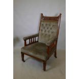 An Arts and Crafts oak show frame armchair, with carved back and shaped slatted sides