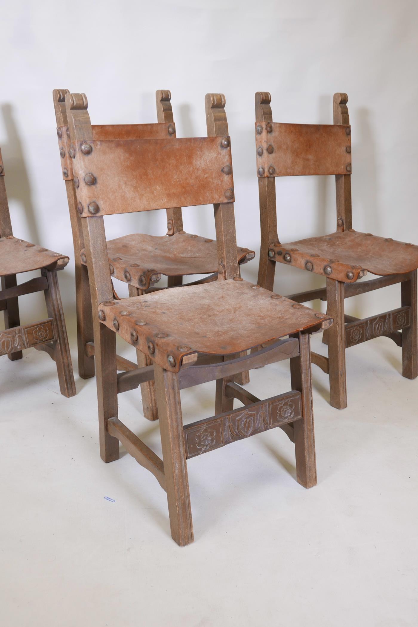 A set of four beechwood monk's chairs, with leather back and seats, iron stud decoration, and carved - Image 3 of 4