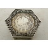 A Chinese hexagonal white metal pill box with coin inset lid chased and engraved with figures and