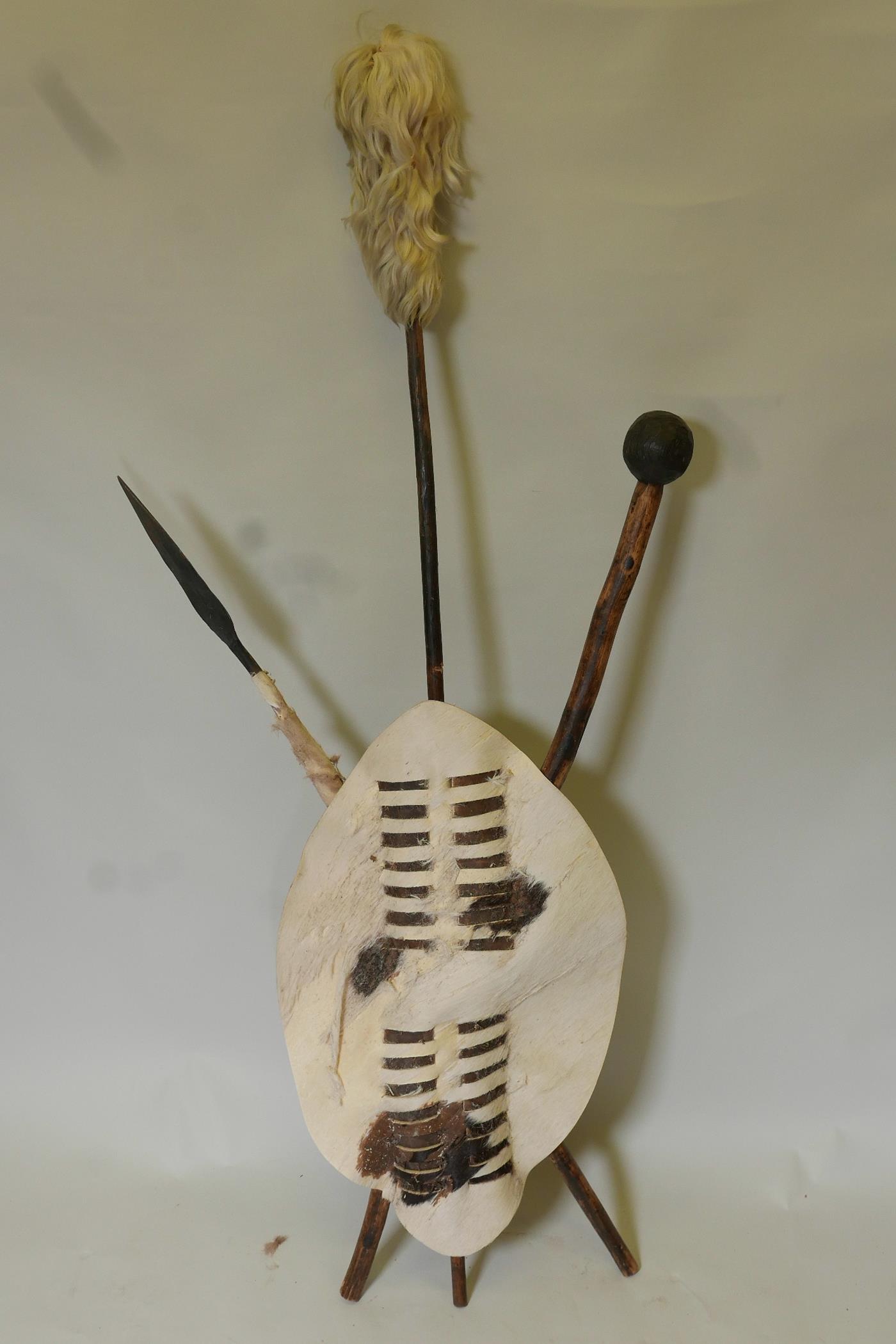 An African ceremonial display of leather shield with crossed club and spear, 7" long