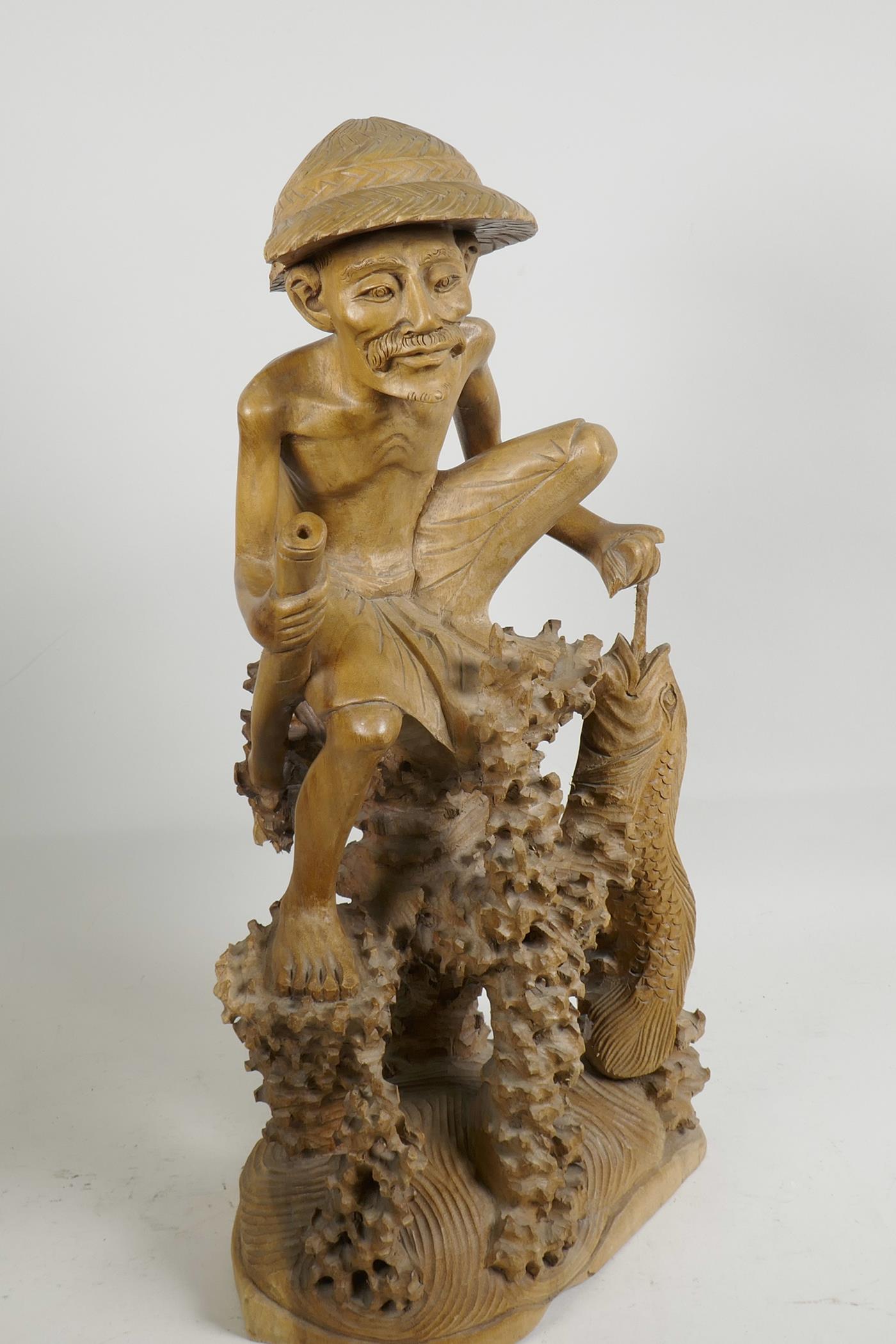 An oriental carved wood figure of a fisherman with large fish, seated on a coral reef, 21" high, A/F - Image 3 of 5