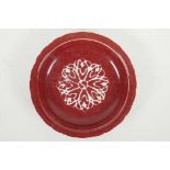 A Chinese red ground porcelain dish with a lobed rim and stylised yin yang decoration, 4 character