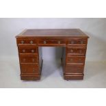 A mahogany nine drawer kneehole pedestal desk with inset writing surface and brass drop ring