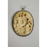 A C19th Cantonese carved ivory pendant in a white metal mount, with carved decoration of figures