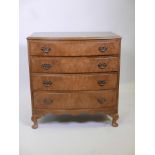 A 1920s mahogany bowfront chest, with four long drawers veneered in walnut and brass fret handles,