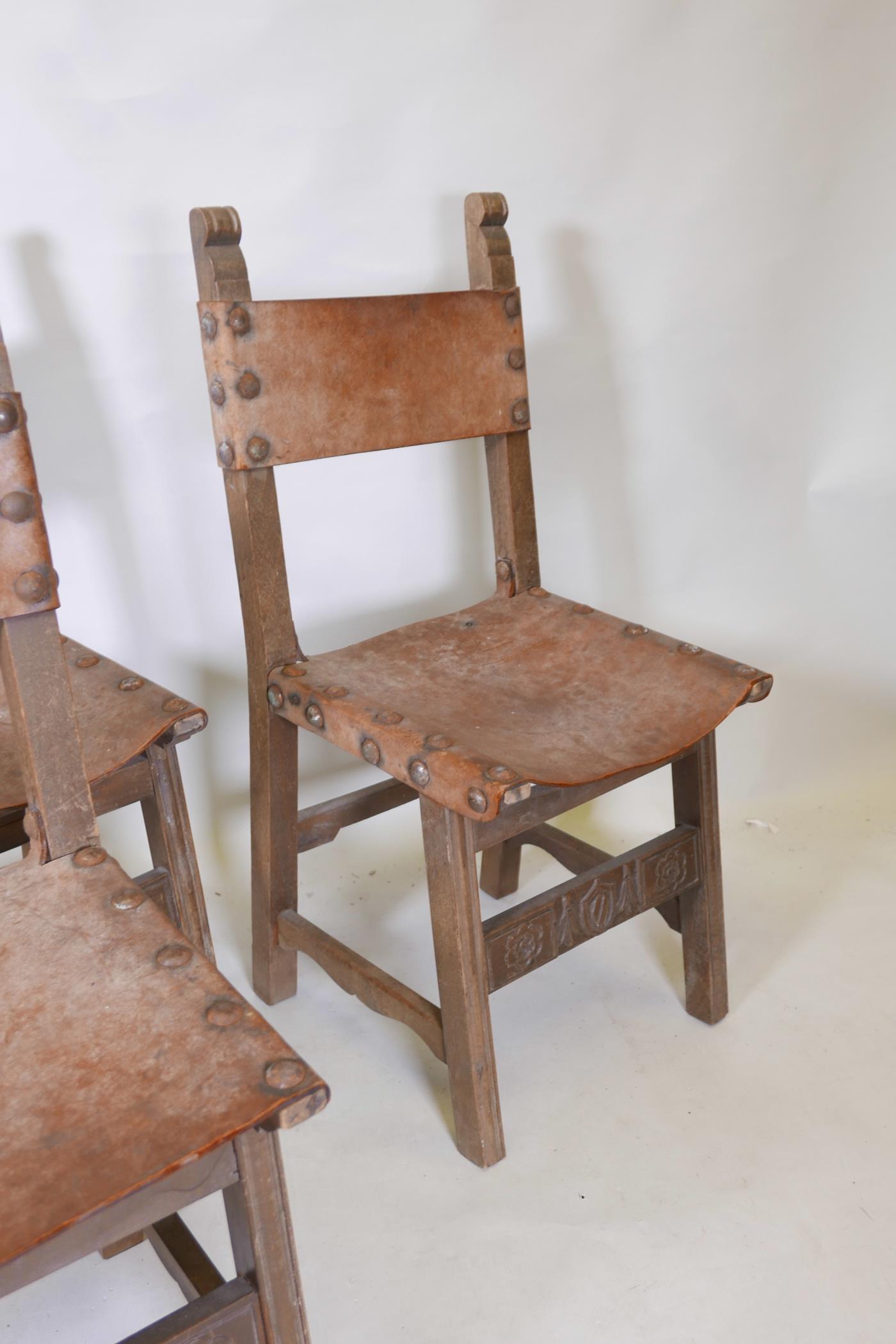 A set of four beechwood monk's chairs, with leather back and seats, iron stud decoration, and carved - Image 4 of 4