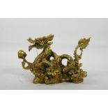 A Chinese gilt metal figure of a dragon clutching the flaming pearl, 8" long