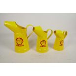 A set of three replica oil jugs decorated with the Shell logo, largest 10" high
