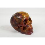 A faux amber skull desk weight with raised magical esoteric symbol decoration, 6½" long x 5½" high