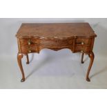 A Burr walnut bowfronted five drawer kneehole dressing table, with shaped top, raised on cabriole