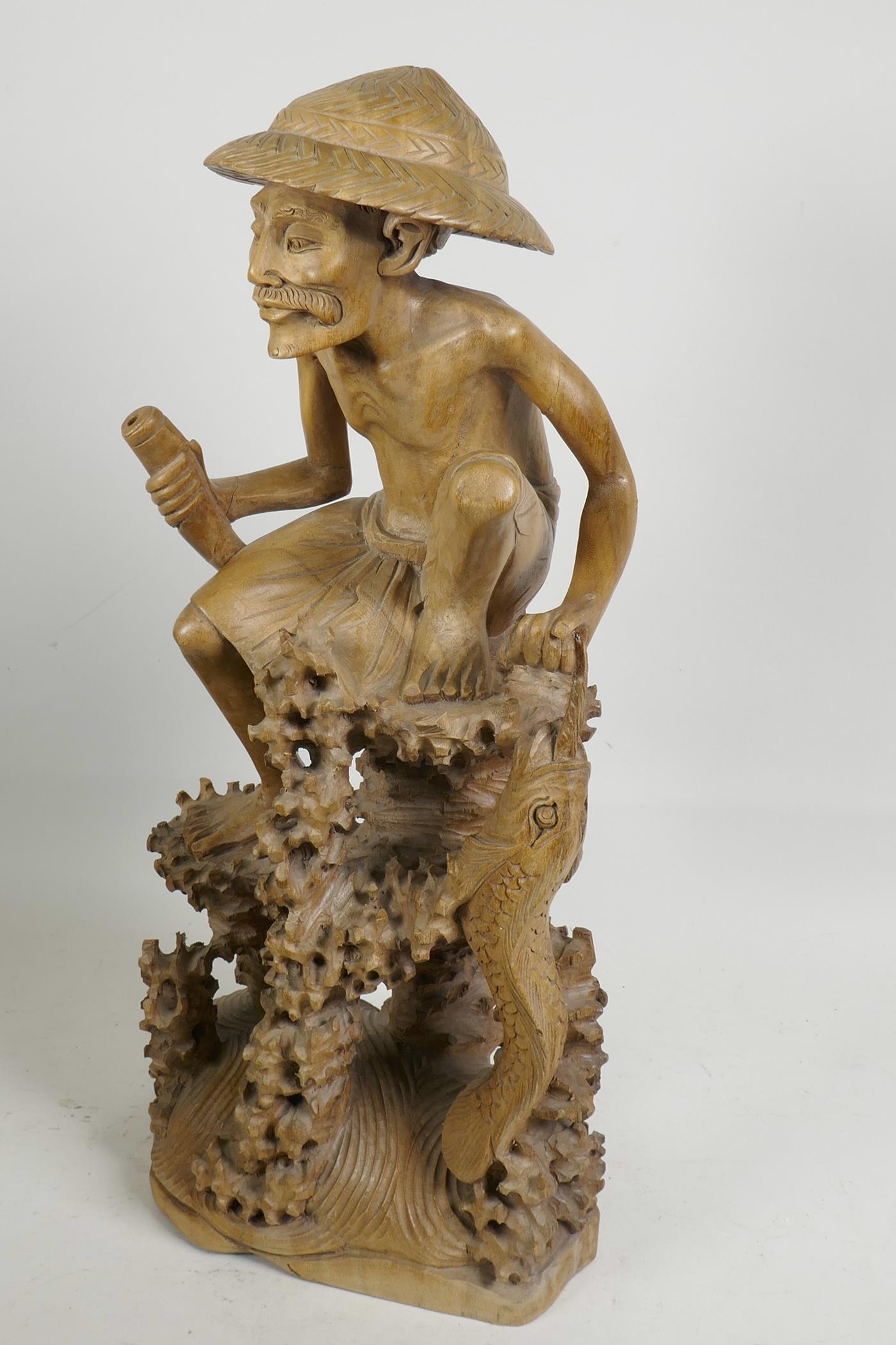 An oriental carved wood figure of a fisherman with large fish, seated on a coral reef, 21" high, A/F - Image 2 of 5