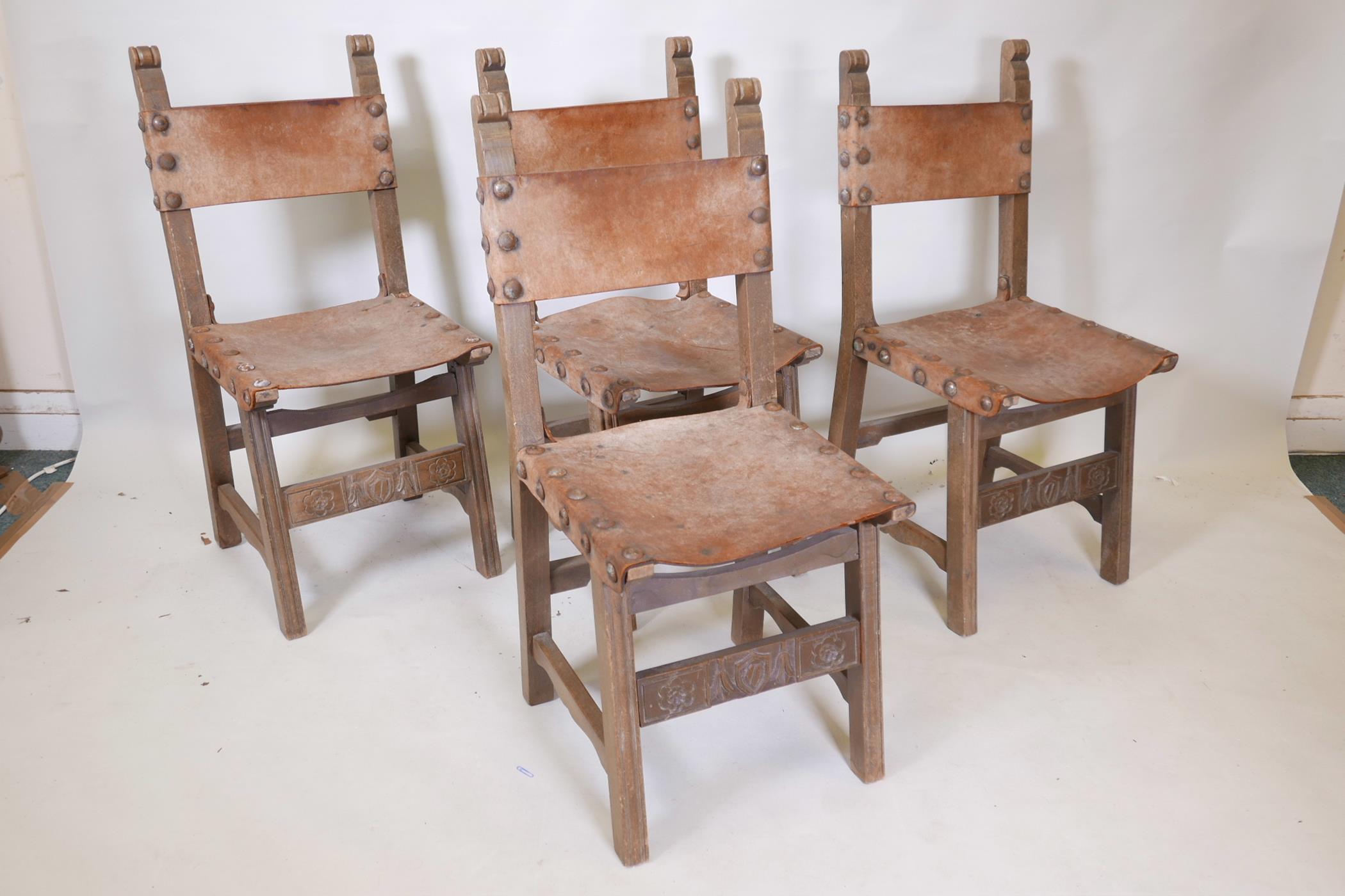 A set of four beechwood monk's chairs, with leather back and seats, iron stud decoration, and carved
