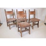 A set of four beechwood monk's chairs, with leather back and seats, iron stud decoration, and carved