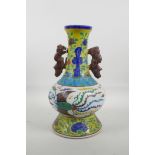 A Chinese porcelain two handled vase with Sancai style glaze and raised decoration of a dragon and