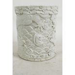 A Chinese cream glazed porcelain brush pot having carved decoration of dragons and carp, impressed