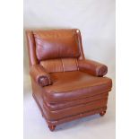 A leather armchair with brass studs and scrolled arms, raised on turned supports