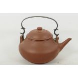 A Chinese red earthenware teapot of plain design with metal handle, inscribed characters to base