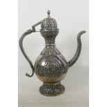 An Indian white metal teapot of traditional form with chased and engraved floral decoration, 14"