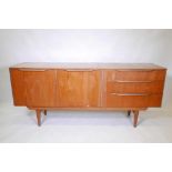 A mid C20th teak sideboard with three long drawers, and a cupboard flanking a fall front centre