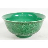 A Chinese green glazed bowl with embossed decoration of dragons, seal mark to base, 6" diameter