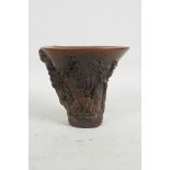 A Chinese faux horn libation cup with carved decoration of figures in a wooded landscape,
