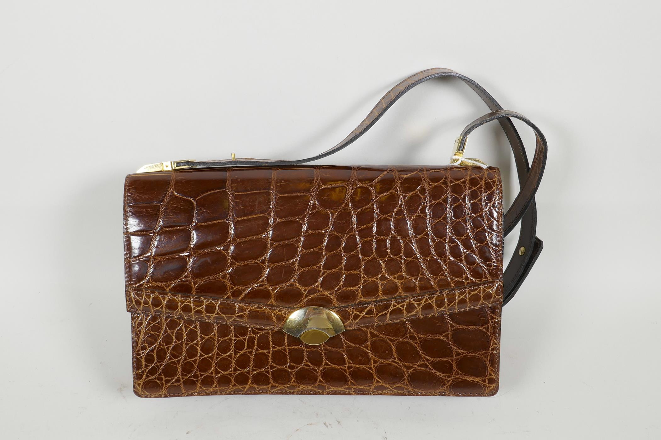 A crocodile skin handbag with brass fittings and shoulder strap, 10" x 6½"