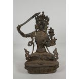 An Indian bronze figure of a seated deity, armed with a large sword, 13" high