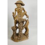 An oriental carved wood figure of a fisherman with large fish, seated on a coral reef, 21" high, A/F