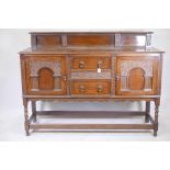 A 1930s Jacobean style oak sideboard, with two cupboards flanking two central drawers, with carved