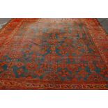 An oriental hand woven wool village carpet with geometric designs on a terracotta and blue field,
