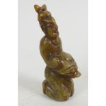 A Chinese carved soapstone amulet carved as a kneeling man holding the head of a large bird, 3" high