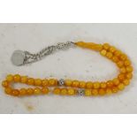 A string of amber coloured Islamic prayer beads with white metal coin tassel