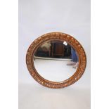 A large circular wall mirror, with moulded decorative scrolling frame and copper/bronze paint