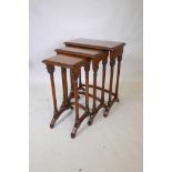 A nest of three figured mahogany acacia wood occasional tables, raised on turned and carved