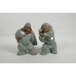 A pair of Chinese porcelain figures of gentlemen, one with a fan, the other with a small barrel,