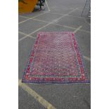 A Persian wool carpet with red and blue borders and all over geometric design, faded, 65" x 92"
