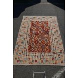 A Konya Kelim flatweave rug with geometric patterned decoration on a red field, with a deep cream