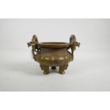 A large Chinese bronzed metal censer of lobed form with two dragon handles and tripod feet,