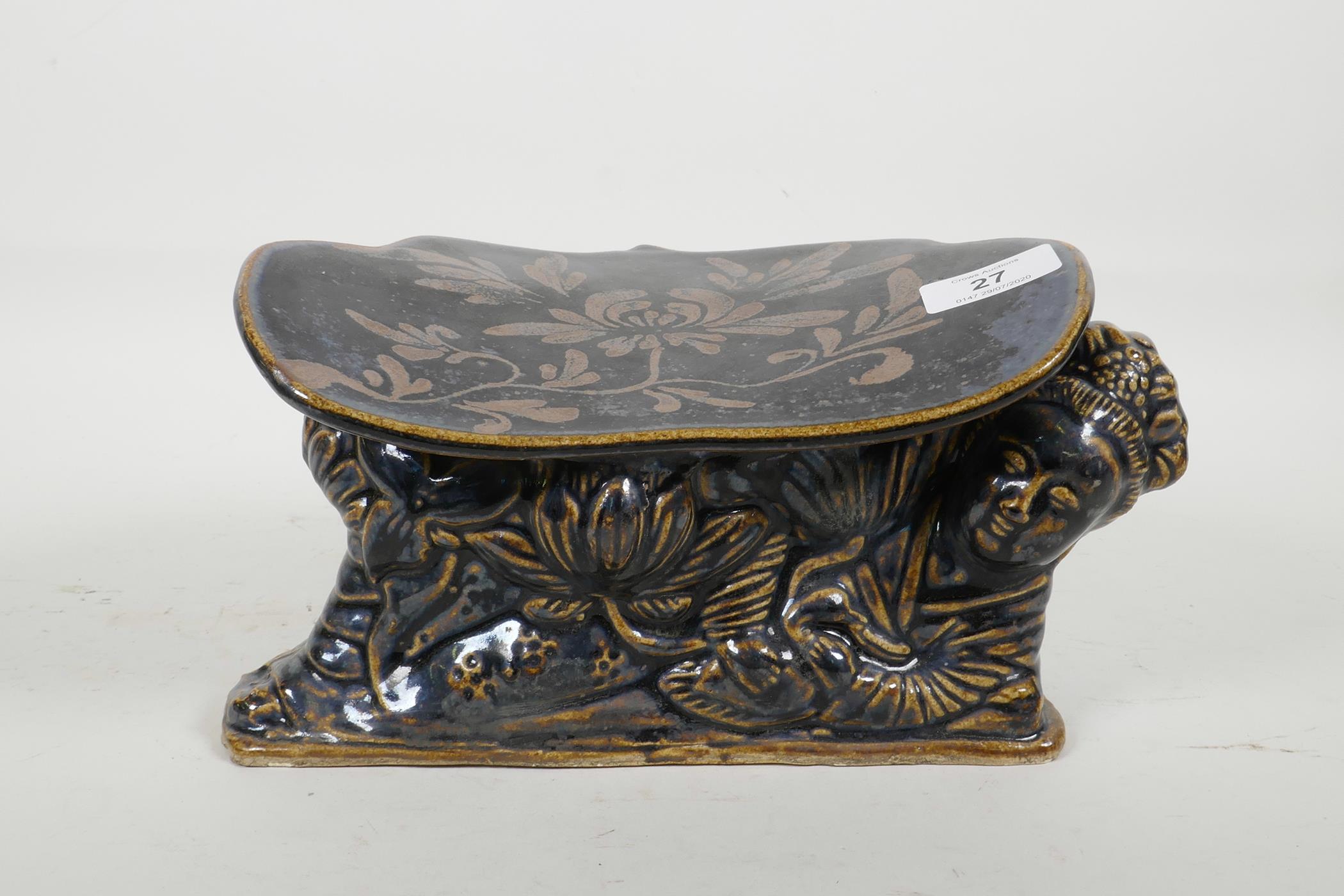 A Chinese Cizhou kiln pottery head rest moulded in the form of a reclining figure, with blue black