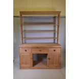 A C19th pitch pine dresser, with delft rack over three drawers and two cupboards flanking an open