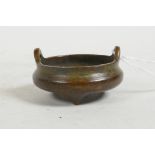 A miniature Chinese bronze censer with phoenix eye handles and tripod supports, impressed mark to