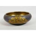 A Kashmiri brass and lacquer bowl with a rolled rim, decorated with gilt floral patterns, signed